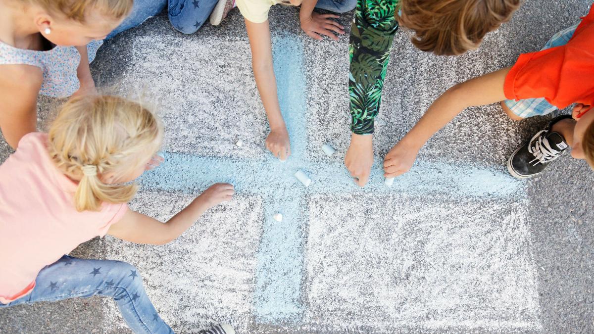 Barnen ritar Finlands flagga till asfalten.