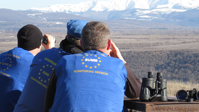 Kuvassa miehet kiikaroivat vuorille.