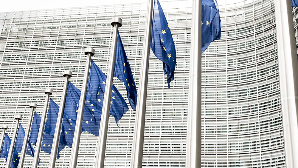 På bilden syns EU-flaggor framför Europeiska kommissionens byggnad