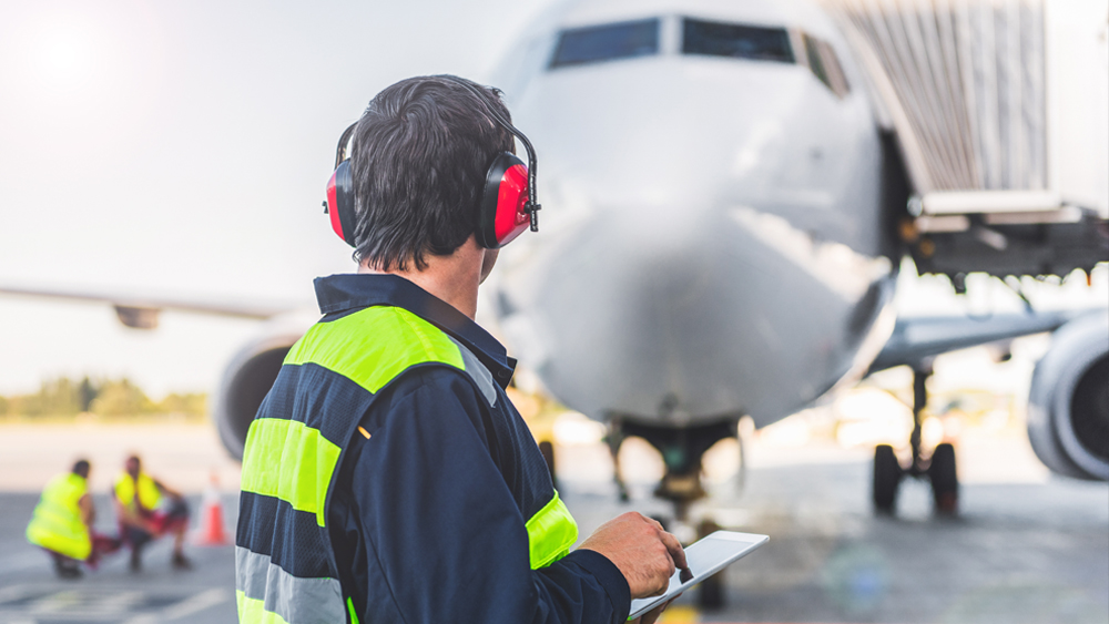 Mies katsoo lentokonetta lentokentällä