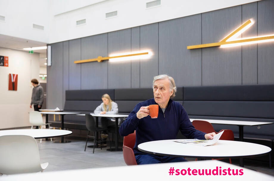 Iäkäs henkilö istuu kahvilla.